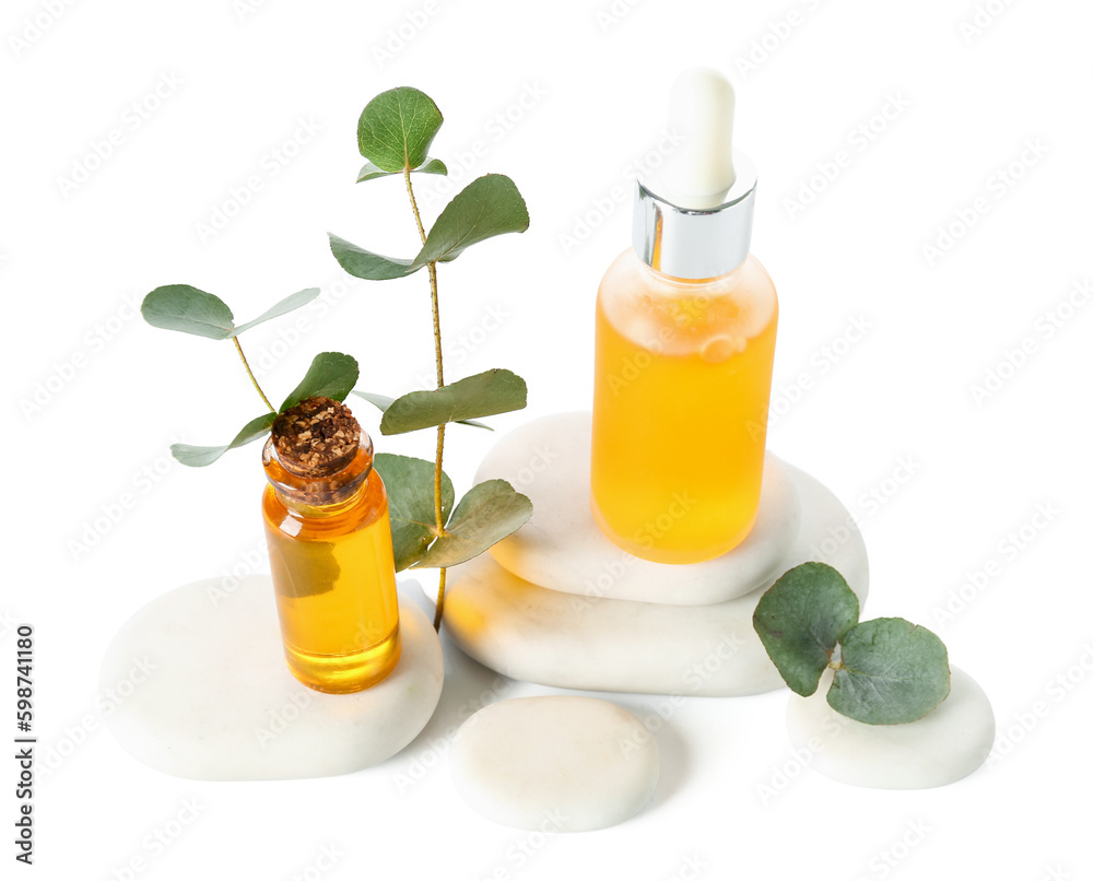 Bottles with cosmetic oil, eucalyptus branch and stones on white background