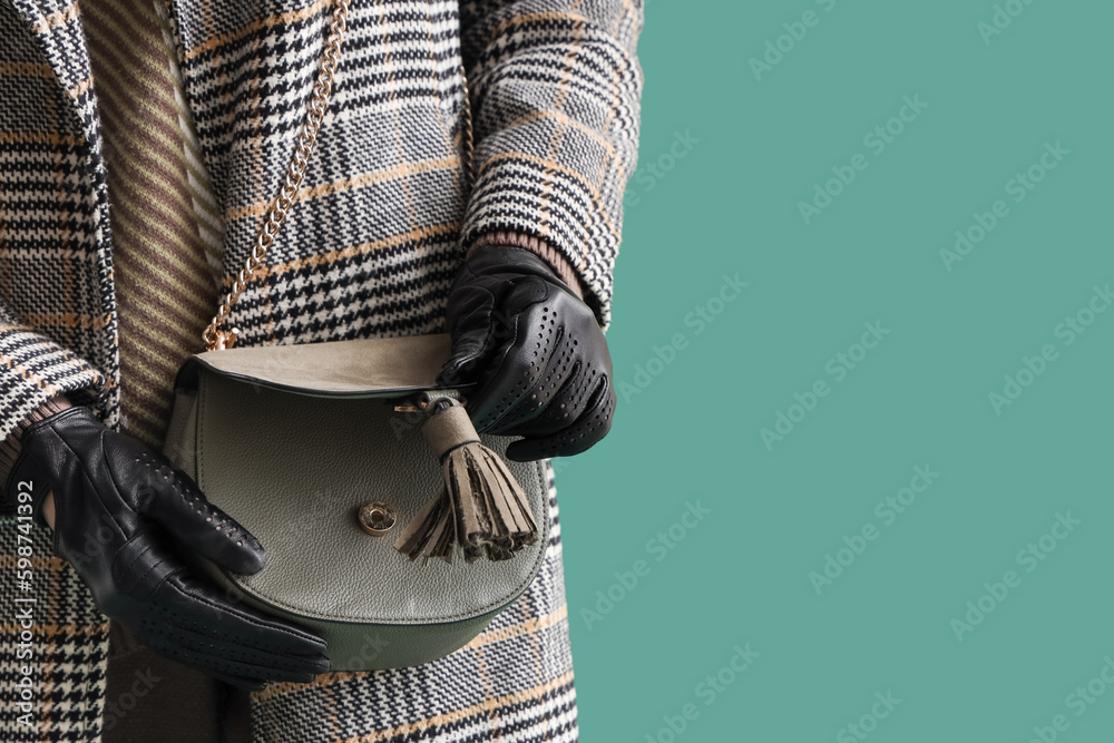 Beautiful woman in leather gloves and with bag on green background, closeup