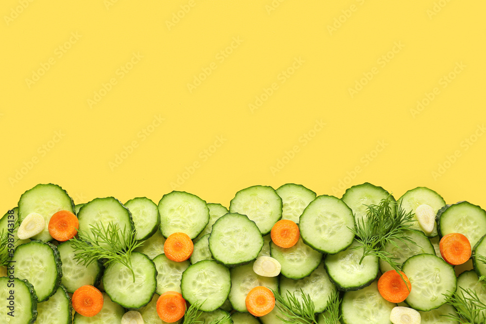 Slices of cucumber with dill and carrot on yellow background