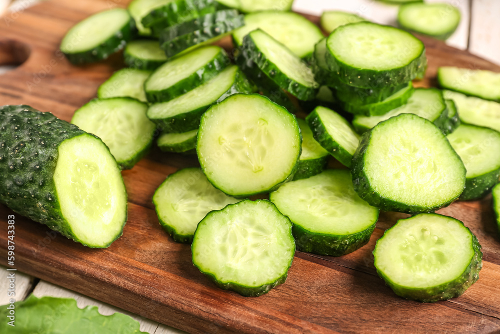 Wooden board with pieces of fresh cucumber on table, closeup