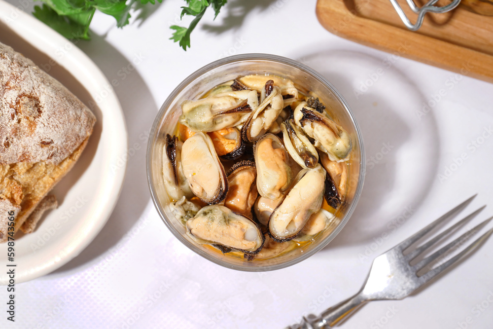 Glass bowl with pickled mussels on white background