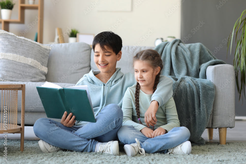 Little boy with his sister reading story at home