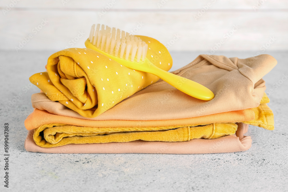 Stack of baby clothes and hair brush on light table