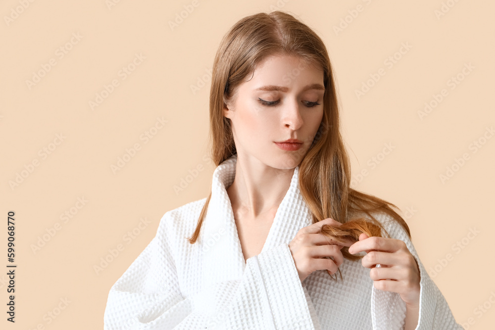 Young woman with hair loss problem on beige background