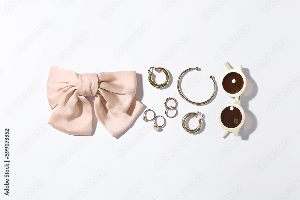 Jewelry with sunglasses and bow on white background