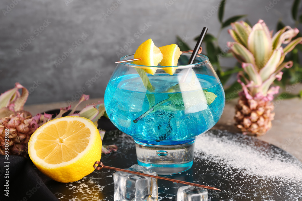 Glass of cocktail with lemon and baby pineapples on board, closeup