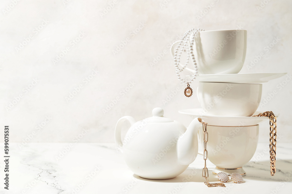 Tea set with stylish jewelry on white table