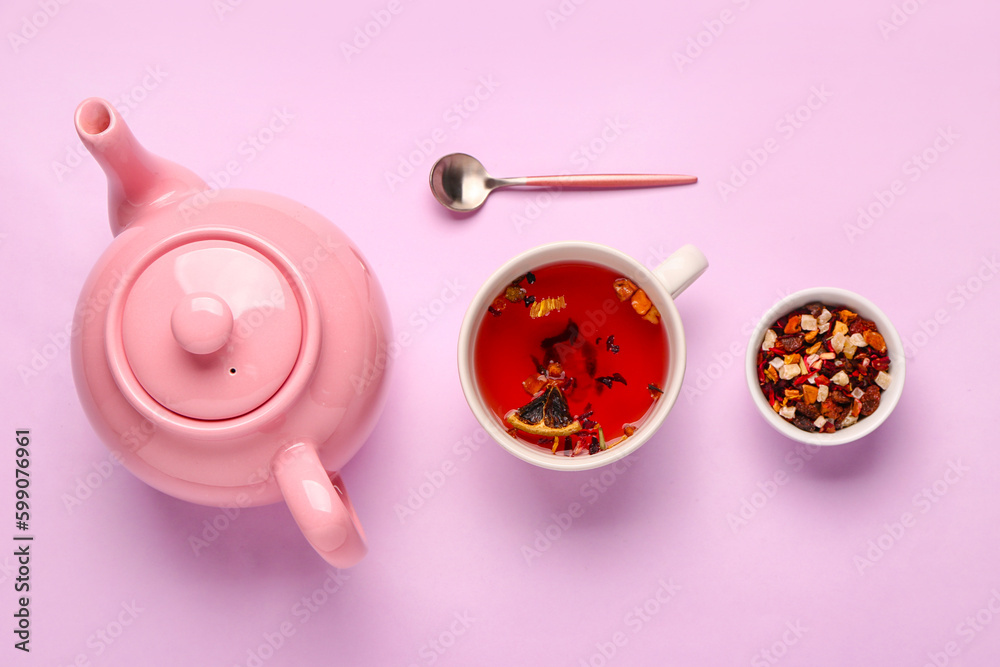 Ceramic teapot with cup of tea and dried fruits on lilac background