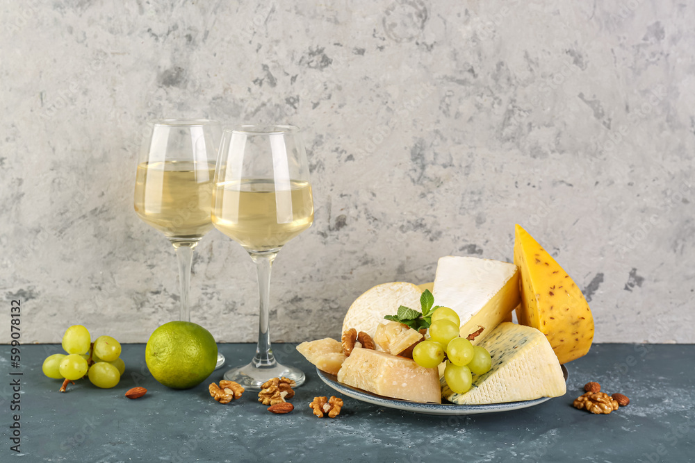 Different types of cheese, fruits and glasses with wine on table