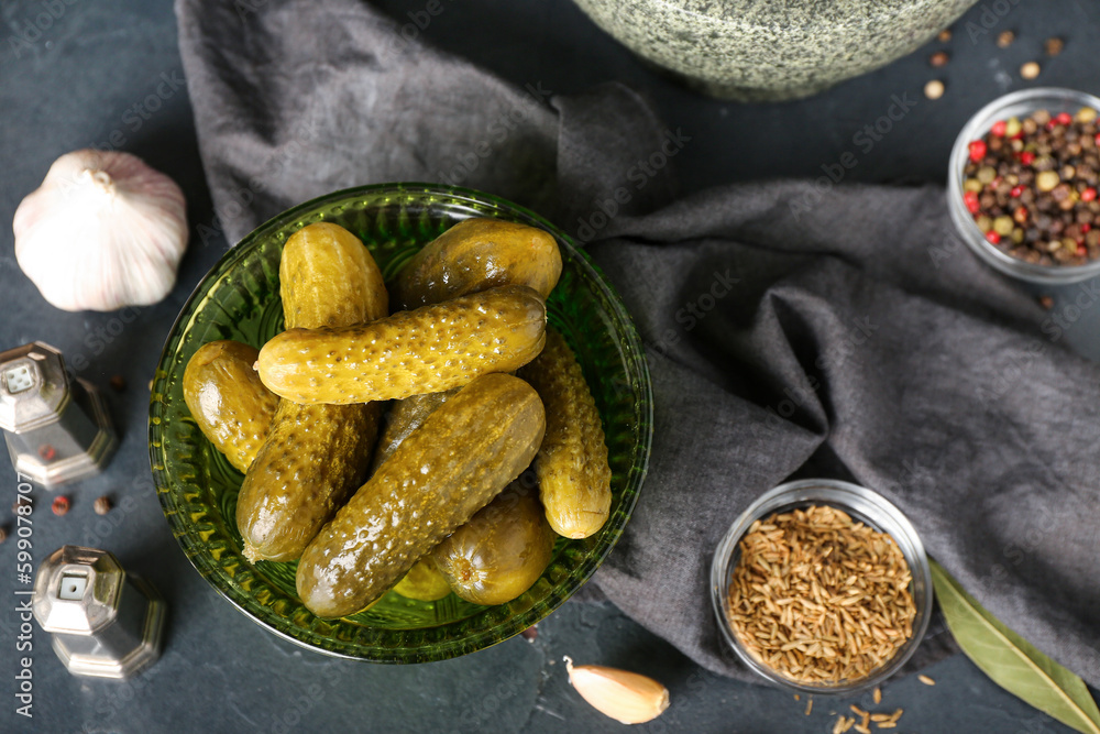 Bowl of tasty canned cucumbers with spices on black table