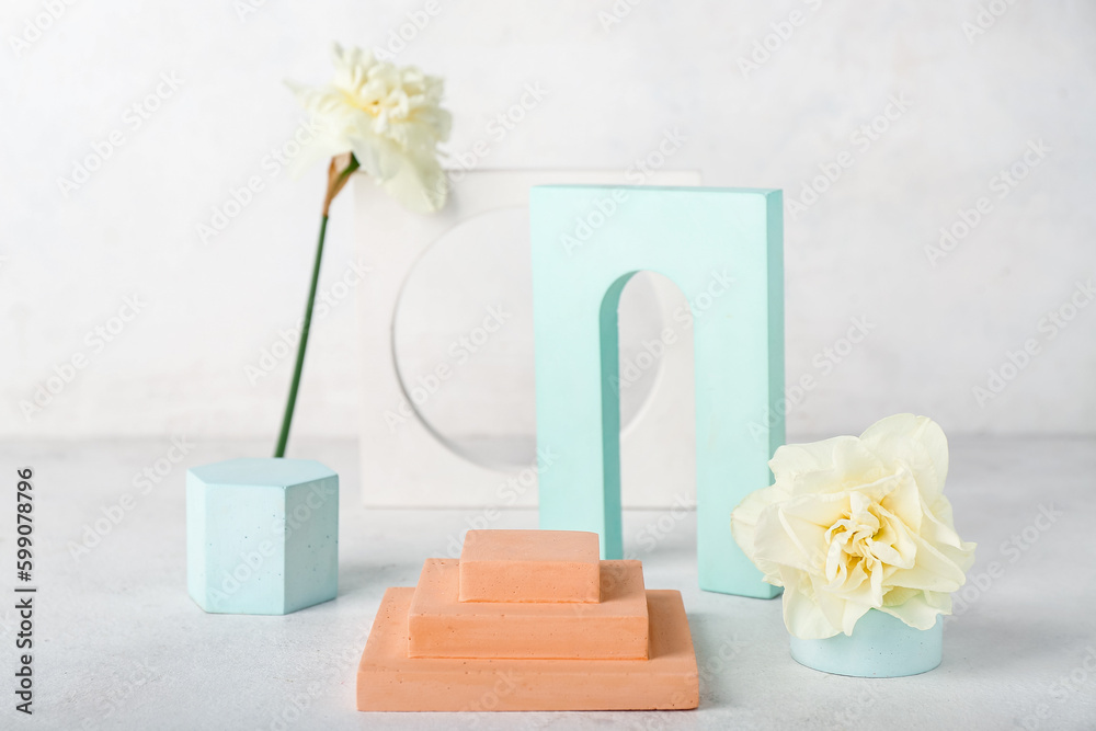 Decorative plaster podiums with daffodils on table against white wall