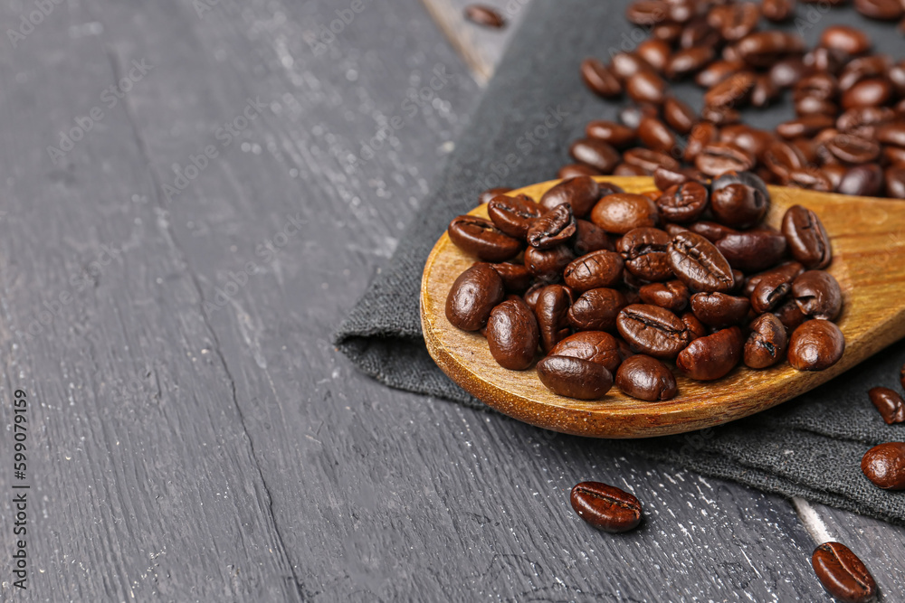 Spoon with coffee beans on dark wooden background