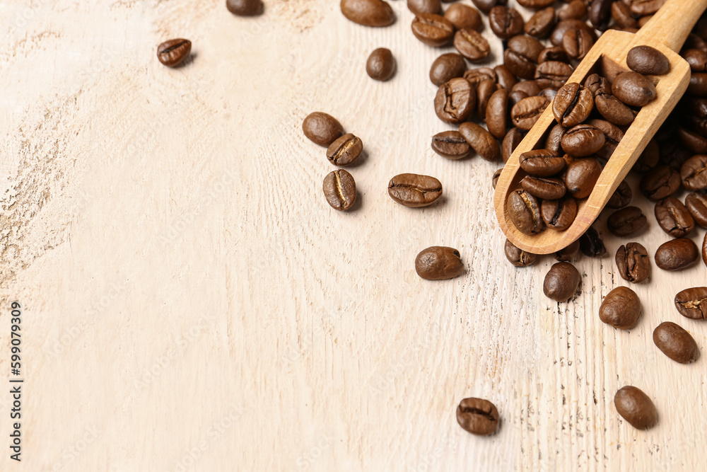 Scoop and coffee beans on light wooden background