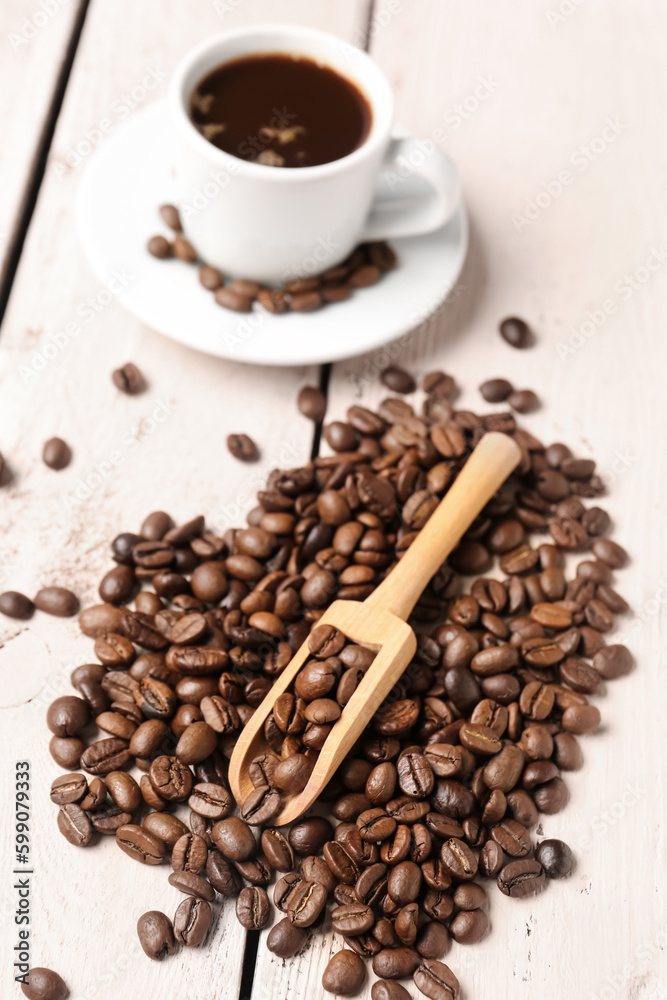 Scoop and coffee beans on light wooden background