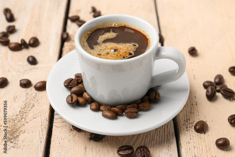 Cup of coffee and beans on light wooden background