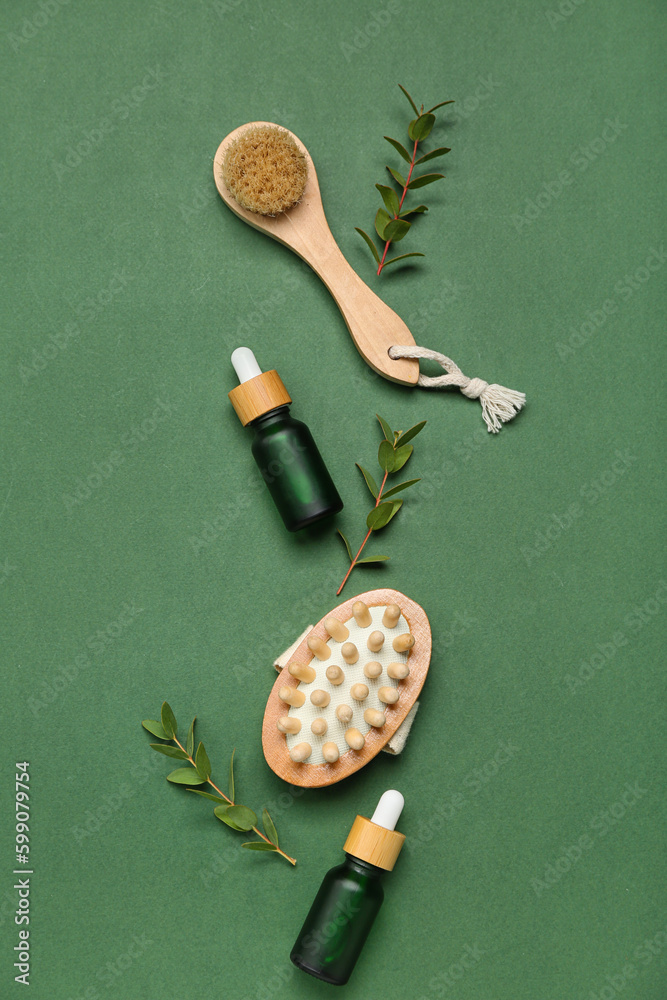 Bottle of cosmetic oil with eucalyptus twigs and massage brushes on dark green background