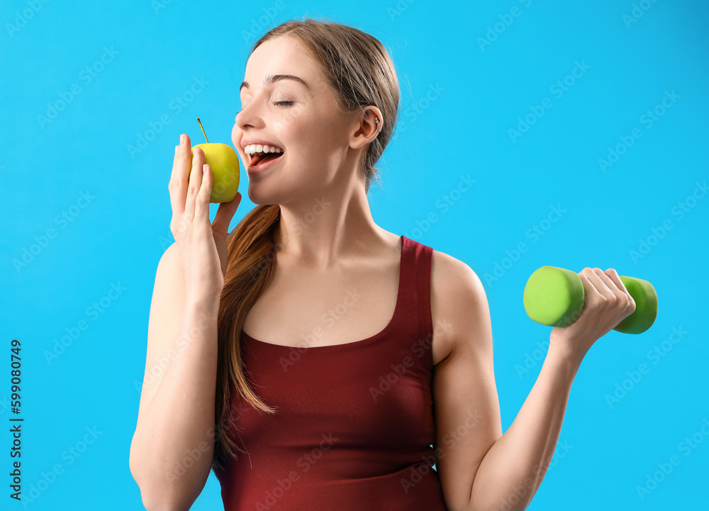 Sporty pregnant woman with apple and dumbbell on blue background