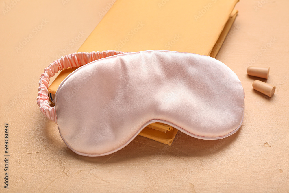 Earplugs with notebook and sleeping mask on beige background