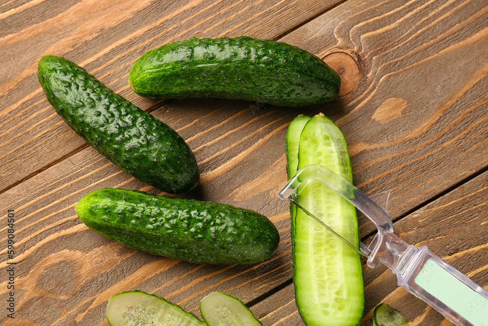 Fresh cucumbers and cut slices on wooden background