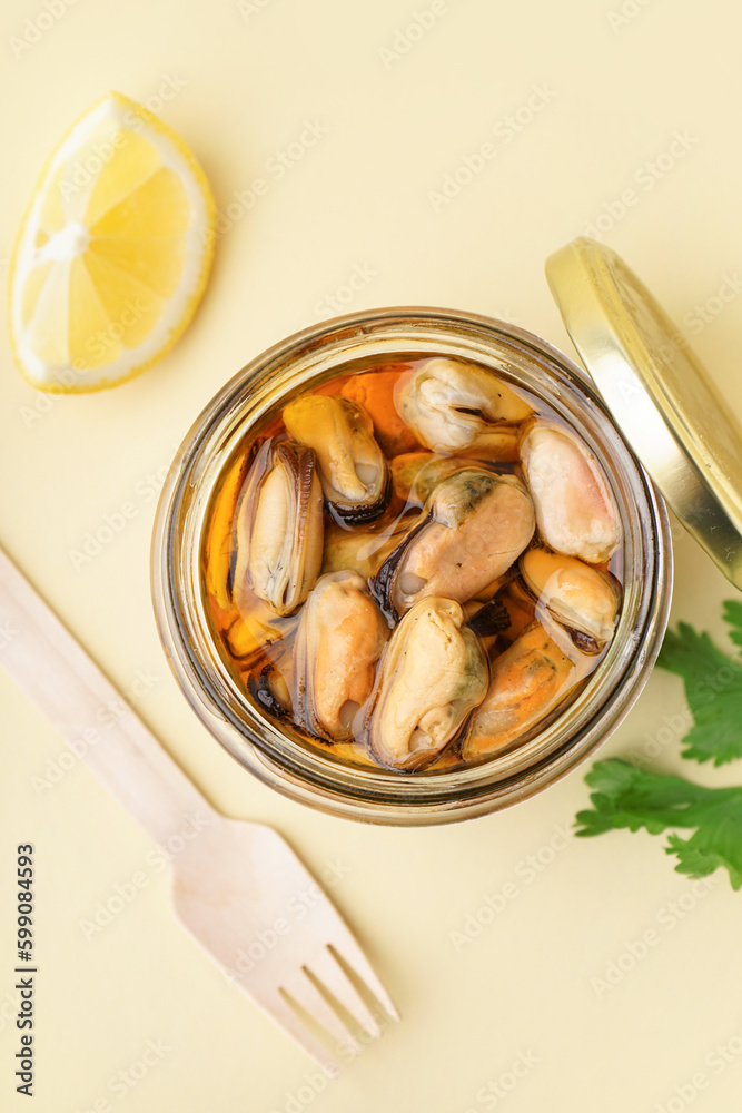 Jar with pickled mussels on beige background