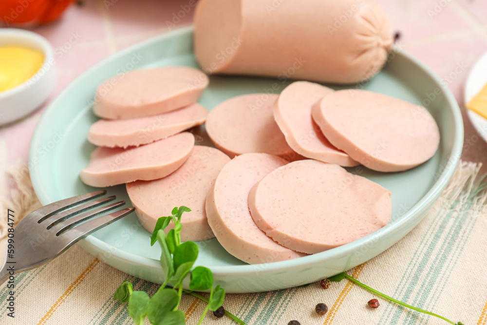 Composition with boiled sausage in plate, green onion and sauce on pink tile table