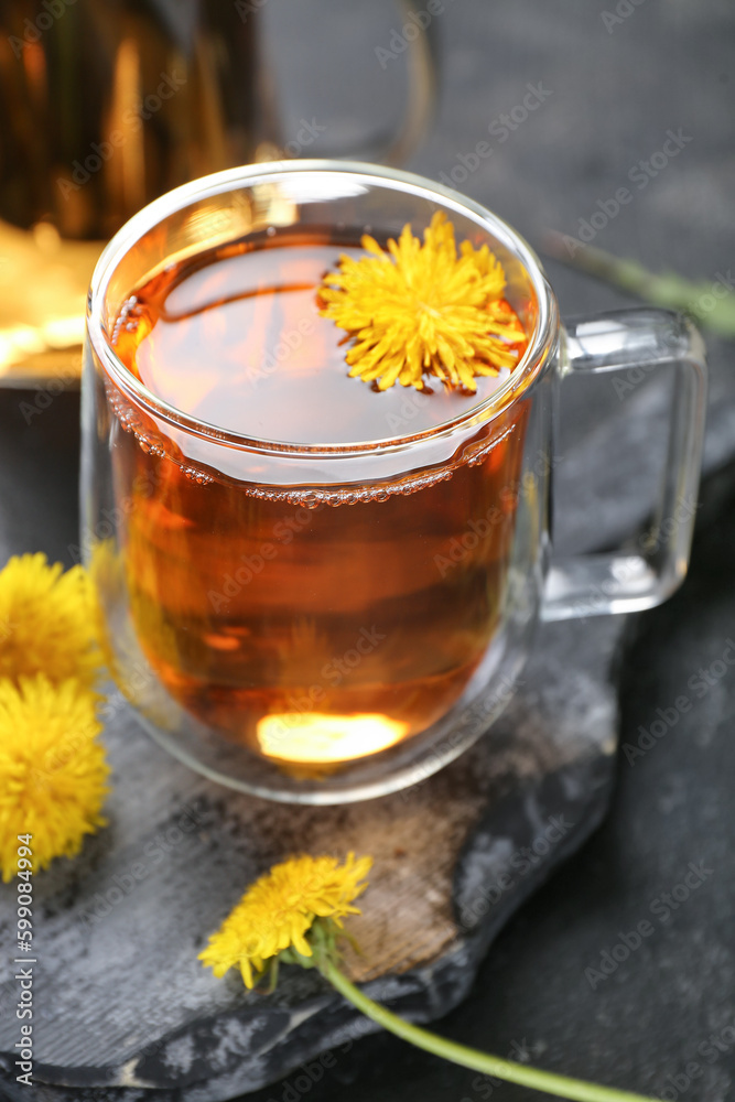 Glass cup of healthy dandelion tea on black background