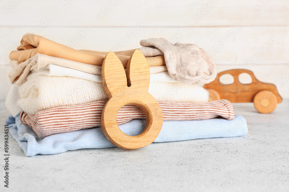 Stack of baby clothes and wooden toys on light table