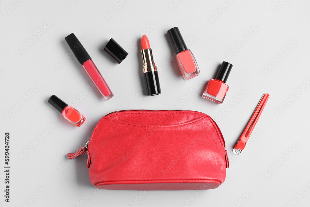 Composition with cosmetic bag, nail polishes and lipsticks on light background