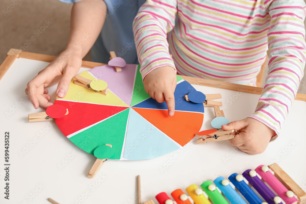 Mother and her little daughter playing matching game with clothespins at home, closeup