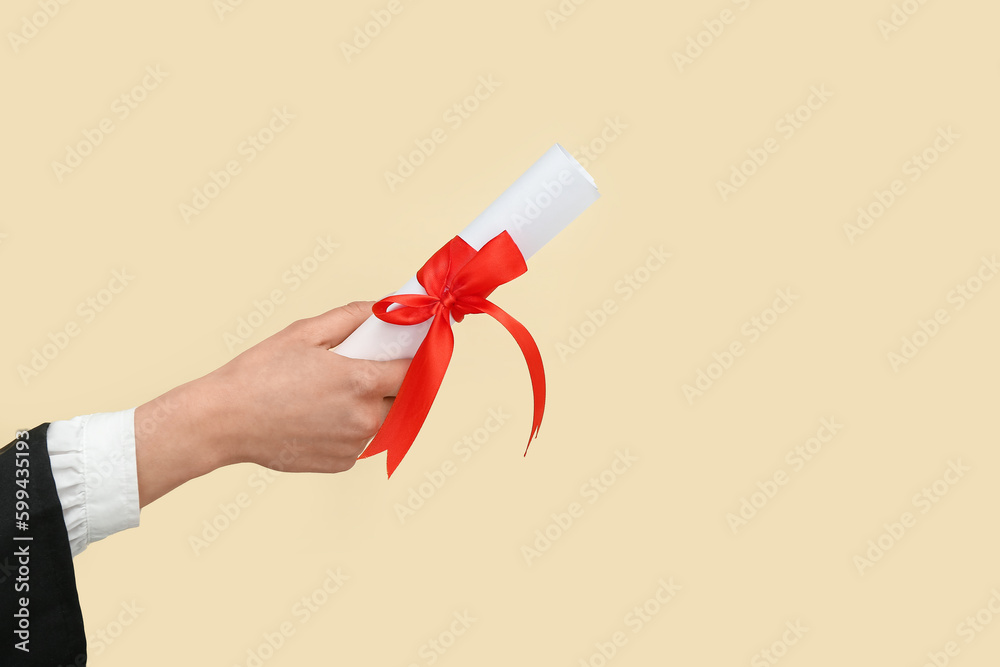 Woman holding diploma with ribbon on yellow background