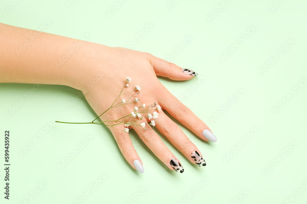 Woman with press-on nails and flowers on green background