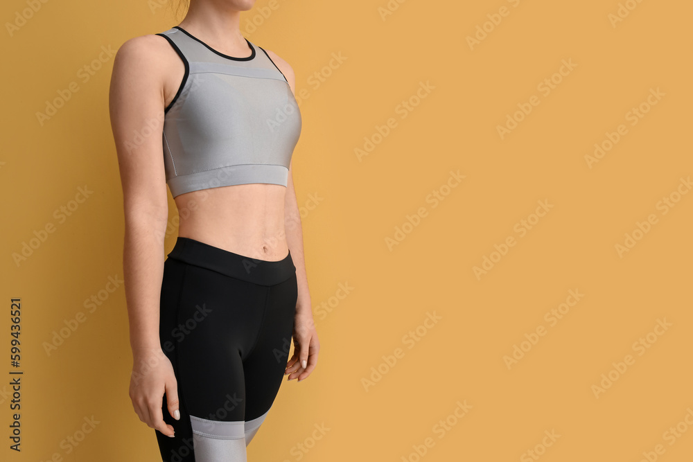 Sporty young woman in leggings on yellow background