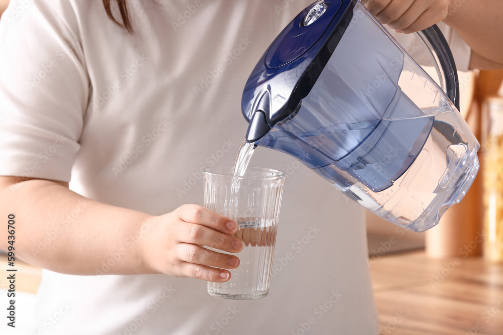 Woman pouring water from filter jug into glass