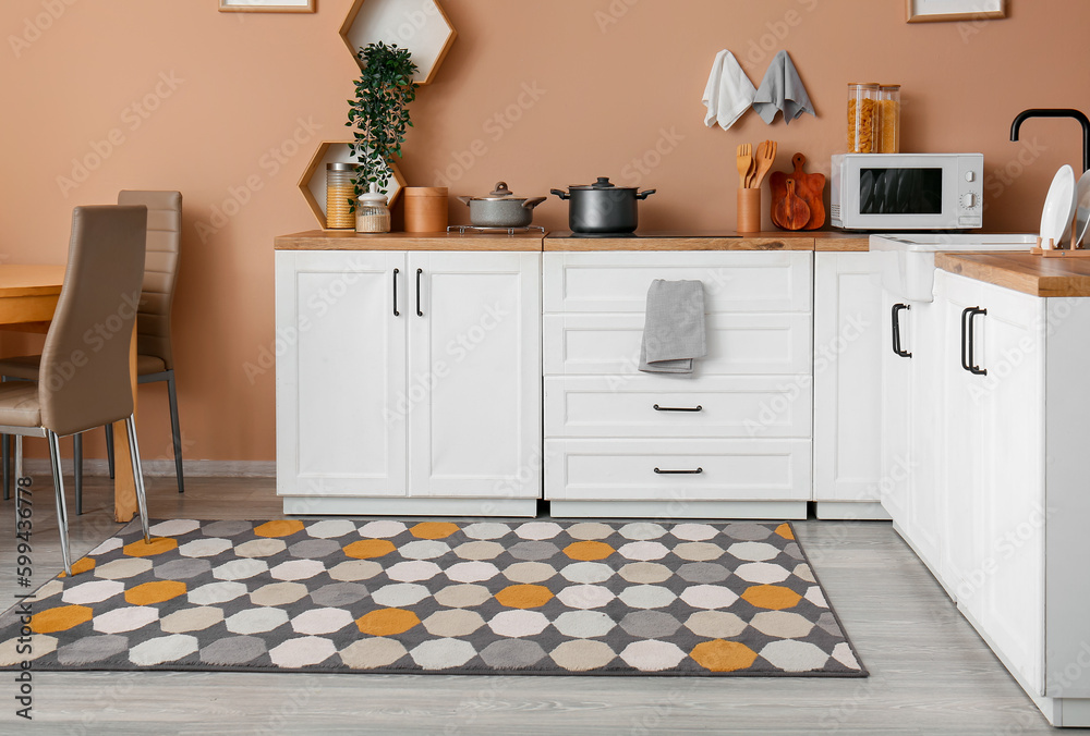 Interior of modern kitchen with white counters and stylish rug