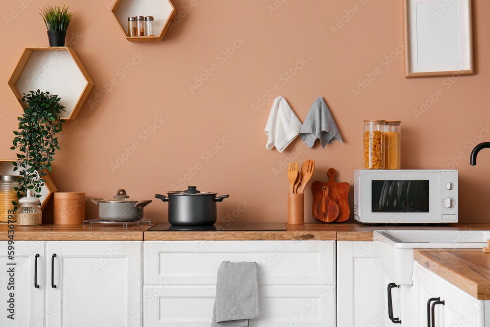 Interior of modern kitchen with white counters, electric stove and microwave oven