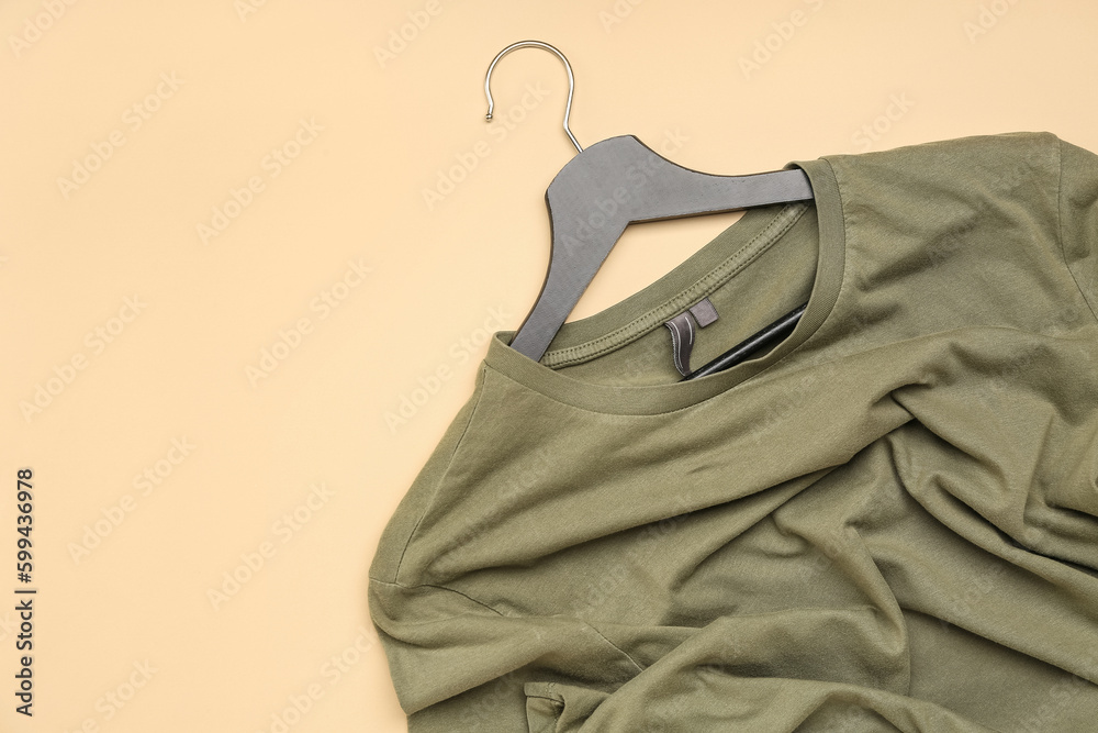 Crumpled green t-shirt with hanger on beige background