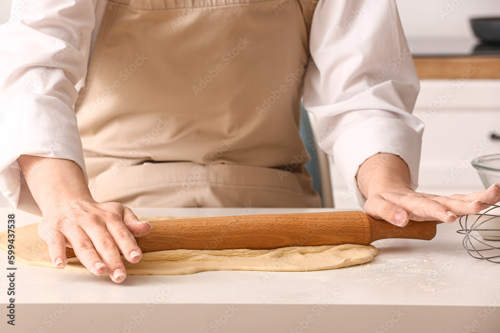 Woman rolling out dough for Italian Grissini at white table in kitchen