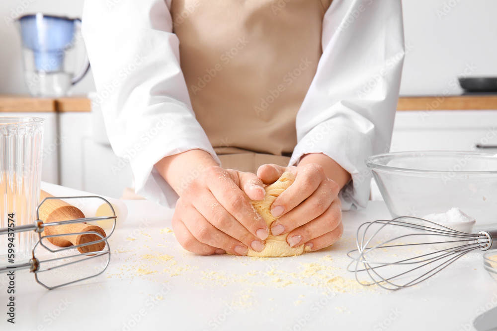 Woman kneading dough for Italian Grissini at white table in kitchen