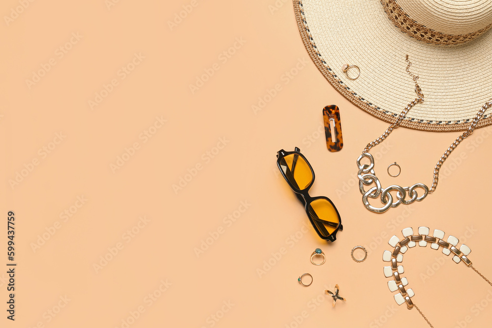 Stylish jewelry with sunglasses and summer hat on beige background