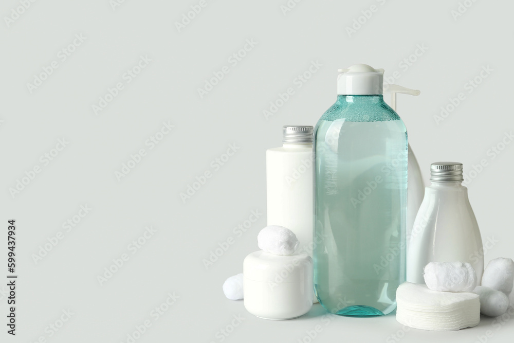 Micellar water with cosmetic products, cotton balls and pads on light background