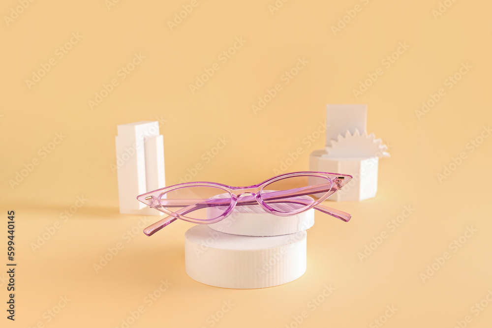 Stylish sunglasses with podiums on beige background