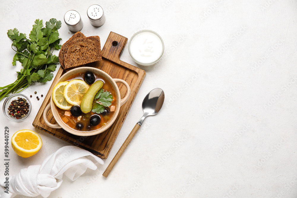 Pot of tasty Hodgepodge soup with bread and sour cream on light background