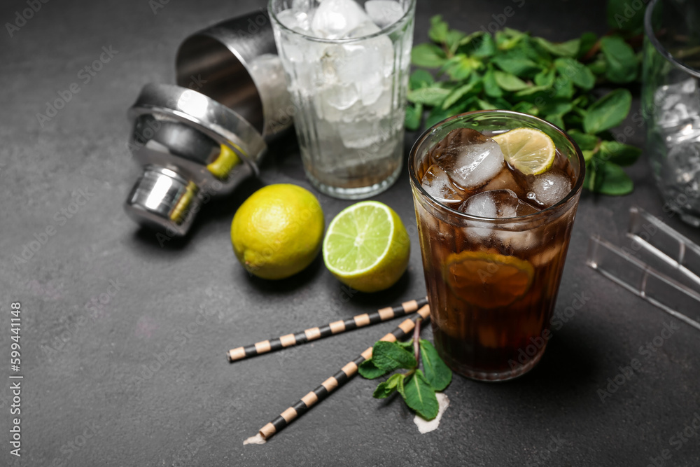 Glass of cold Cuba Libre cocktail on dark background