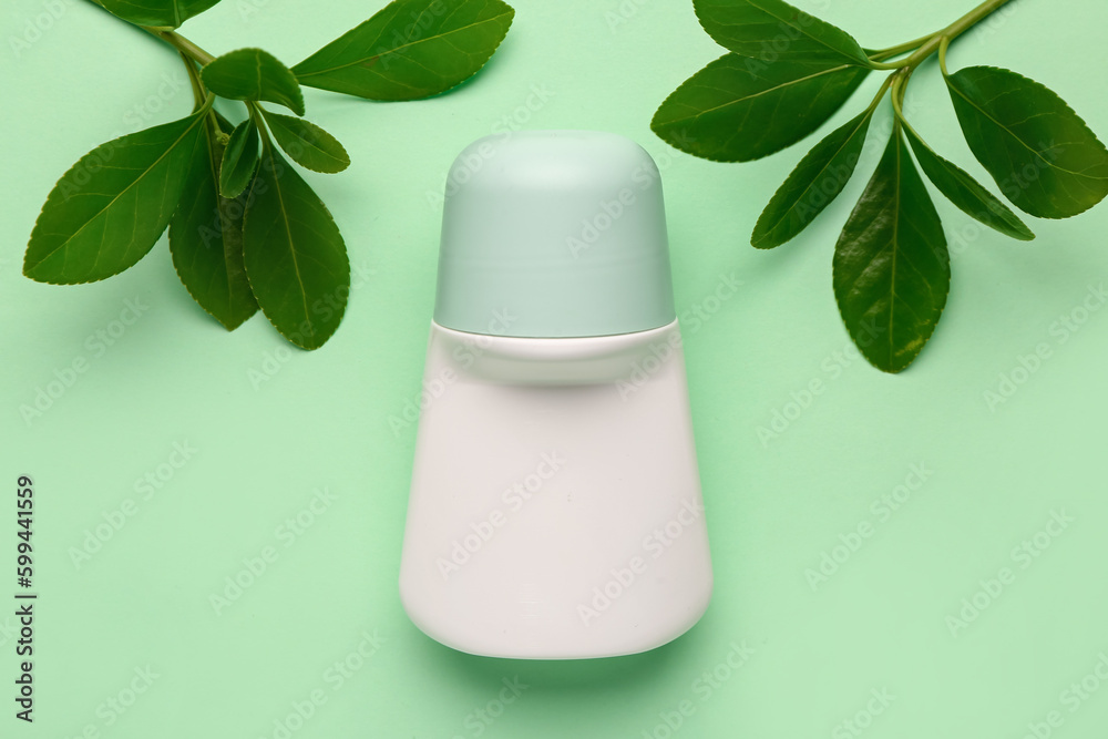 Deodorant with plant twigs on light green background