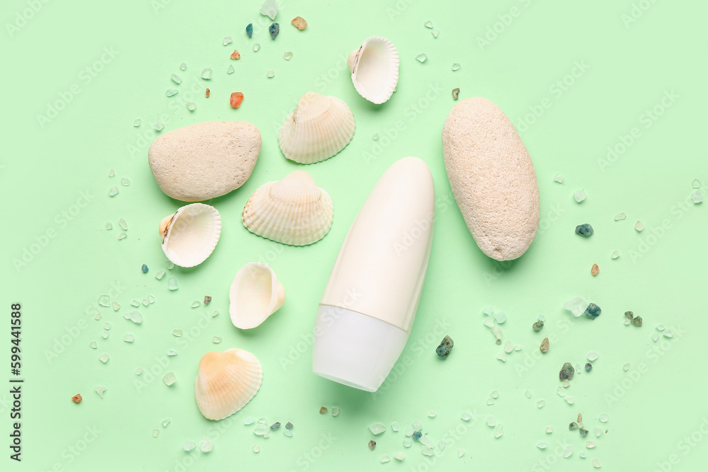 Deodorant with shells, stones and sea salt on light green background