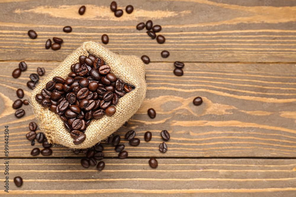 Bag with coffee beans on wooden background