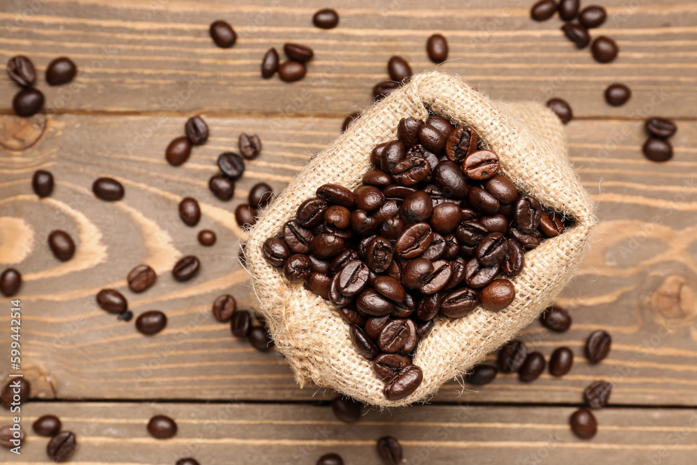 Bag with coffee beans on wooden background