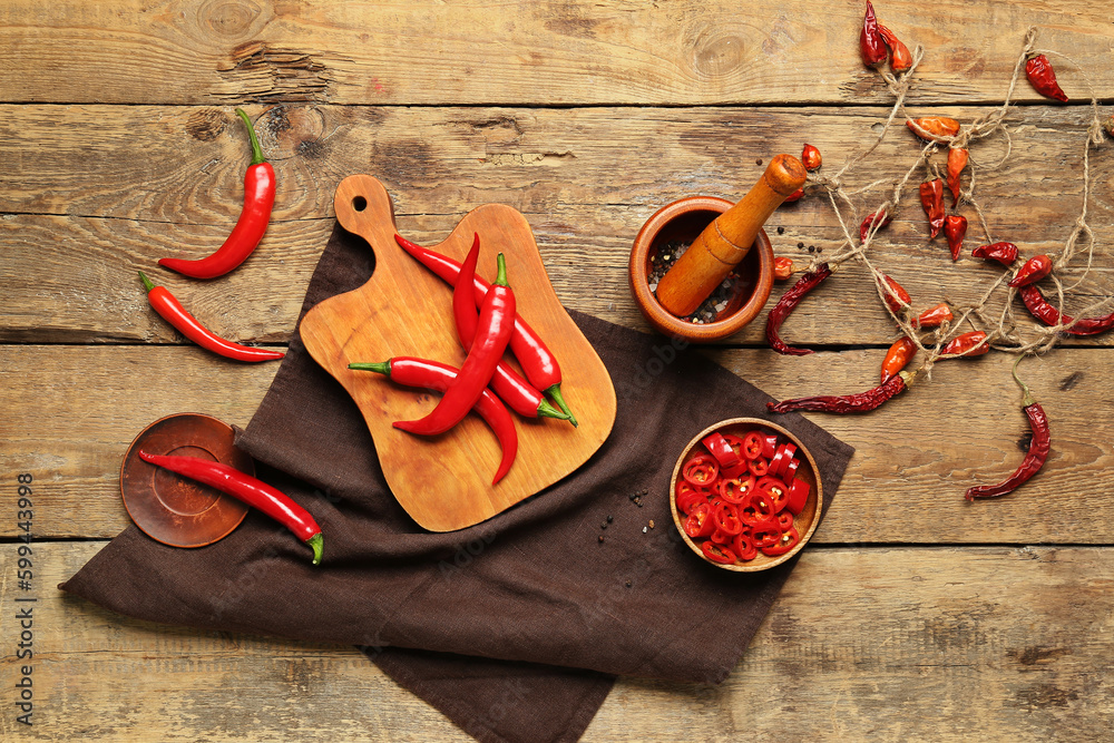 Board of fresh and dry hot chili peppers with mortar on brown wooden background