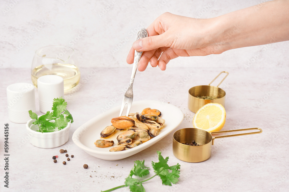 Female hand and pickled mussels on white background