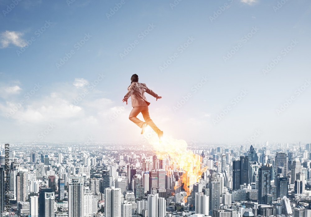 Businessman in suit and aviator hat flying in sky